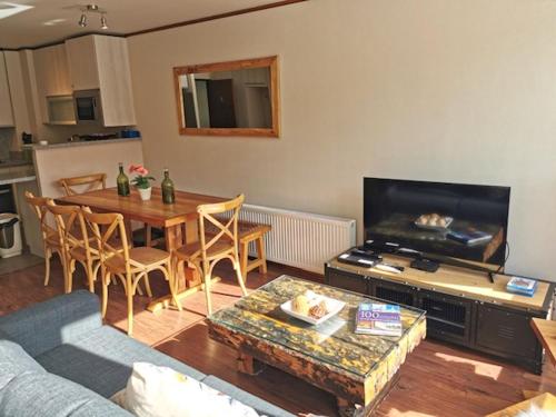 a living room with a table and a television at DEPARTAMENTOS TERMAS DE CHILLAN in Nevados de Chillan