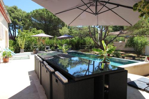 un patio avec un parasol et une piscine dans l'établissement Au cœur de la Roque d'Anthéron - Aux portes du Lubéron, à La Roque-dʼAnthéron