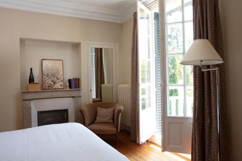a bedroom with a bed and a chair and a fireplace at Le Jardin des Plumes in Giverny