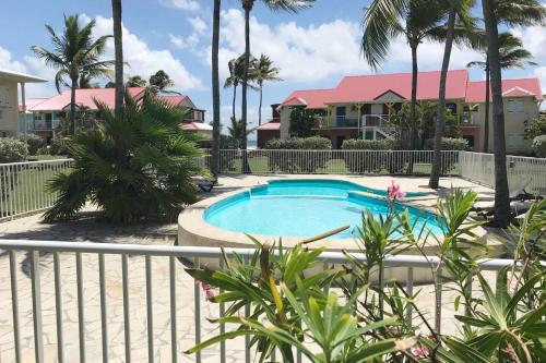 a swimming pool with palm trees and houses at Crystal Beach, vue mer, accès direct plage et piscine, clim in Sèze