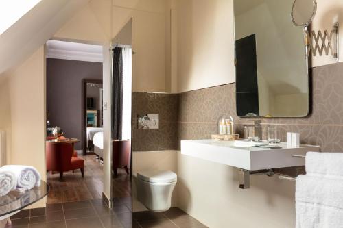 a bathroom with a sink and a toilet and a mirror at Le Jardin des Plumes in Giverny