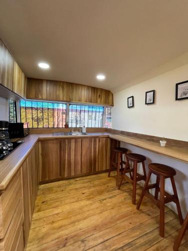 a kitchen with wooden cabinets and a bar with stools at BusHotel Puerto Viejo with private Hot Tube very close to town in Puerto Viejo