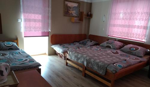 two beds in a room with pink curtains at Baltazar in Łeba