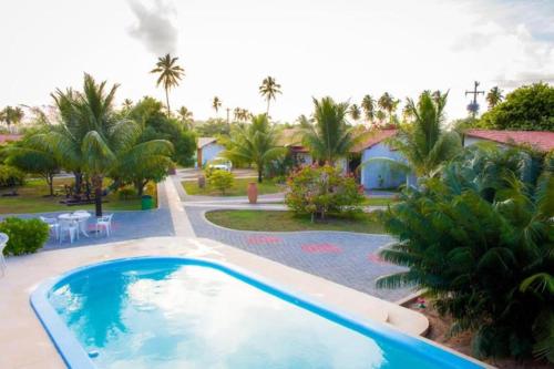 un complejo con piscina y palmeras en Pousada Kaluanã, en Japaratinga