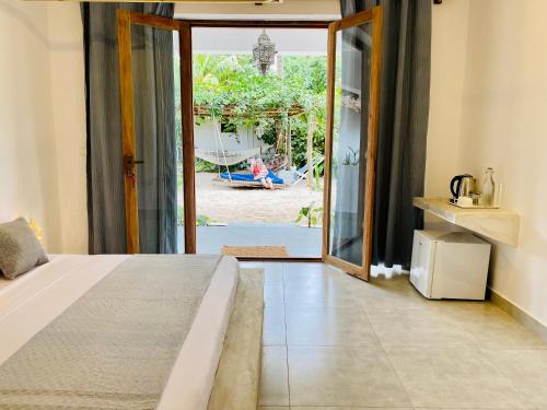 a bedroom with a bed and a sliding glass door at Badolina Bungalows in Nungwi