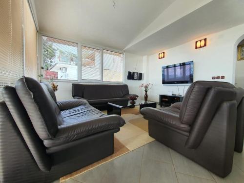 a living room with two leather chairs and a tv at Villa Aurora in Ohrid