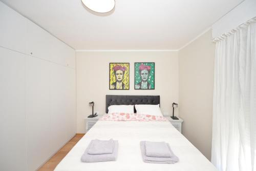 a white bedroom with a bed with two towels on it at The Nest - Urban Family place in Kotor