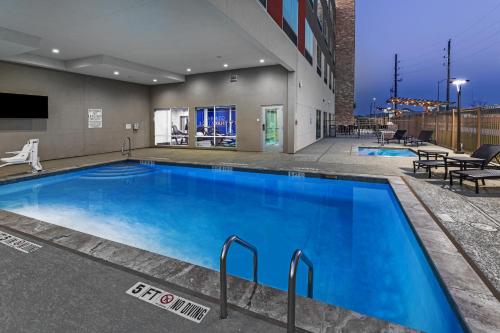 a large blue swimming pool in a building at Holiday Inn Express & Suites - Houston SW - Rosenberg, an IHG Hotel in Rosenberg