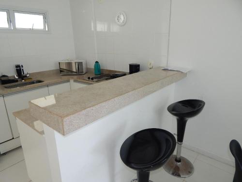 a kitchen with a counter top and two stools at Charmoso e confortável 1 quarto/frente Mar - Mandai / Inicio da praia do Forte - CF07 in Cabo Frio