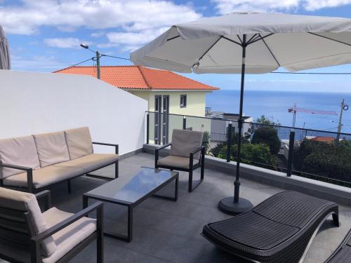 a patio with chairs and an umbrella and the ocean at Calheta Ocean View Apartments 1 - Air Condition in Estreito da Calheta