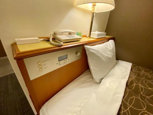 uma cama com telefone e um candeeiro em cima em Az Inn Fukui - Vacation STAY 65924v em Fukui