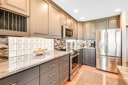 a kitchen with gray cabinets and a stainless steel refrigerator at Misty Lady at Water's Edge in Freeland