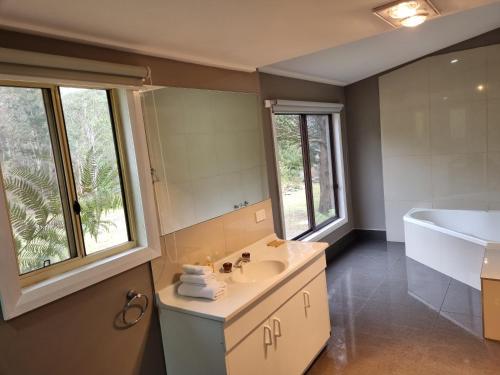 a bathroom with a sink and a tub and a mirror at Roland B&B in Claude Road