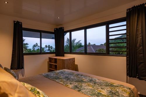 a bedroom with a bed and large windows at Hidden Mo'a Villa in Bora Bora