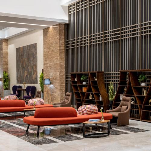 a lobby of a hotel with red chairs and tables at Novotel Makkah Thakher City in Makkah