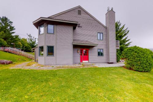 a house with a red door on a green yard at Slopeside 705 in Jay