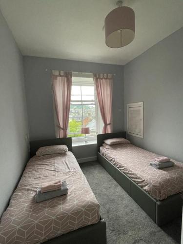 a bedroom with two beds and a window at Our Wee Getaway in Rothesay