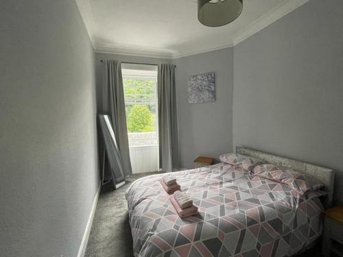 a bedroom with a bed with pink and white sheets and a window at Our Wee Getaway in Rothesay