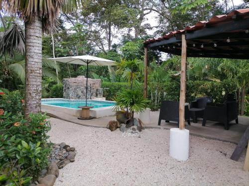 a swimming pool with an umbrella and a table and chairs at Casa el Colibrí in Parrita