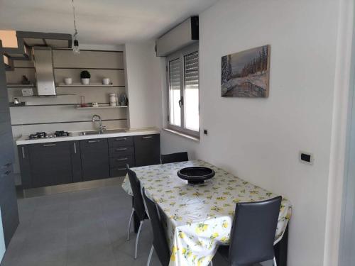 een keuken met een tafel met stoelen en een wastafel bij Casa vacanza HADA in San Giacomo degli Schiavoni