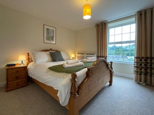 - une chambre avec un grand lit et une fenêtre dans l'établissement Glasfryn Cottage Dolgellau, à Dolgellau