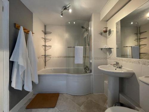 La salle de bains est pourvue d'une baignoire, d'un lavabo et d'une douche. dans l'établissement Glasfryn Cottage Dolgellau, à Dolgellau