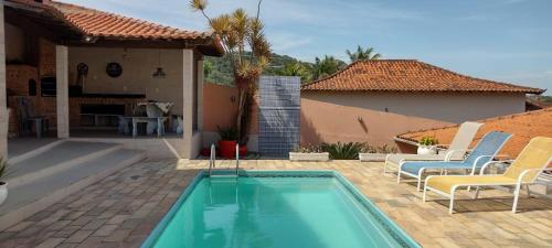 a swimming pool with chairs and a house at Casa com piscina com linda vista panorâmica in Araruama