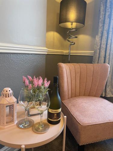 a table with a bottle of wine and a chair at Courtyard Holiday Apartments in Belper