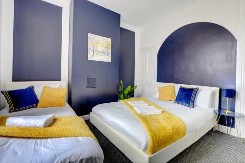 duas camas num quarto com azul e branco em Cheerful 2 Bedroom Home, Sleeps 5 Guest Comfy, 1x Double Bed, 3x Single Beds, Free Parking, Free WiFi, Suitable For Business, Leisure Guest,Coventry, Midlands em Coventry