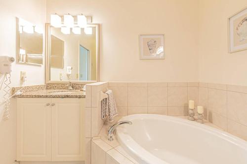 a bathroom with a tub and a sink and a mirror at Greenlinks-Lely-Building 1200 in Lely Resort