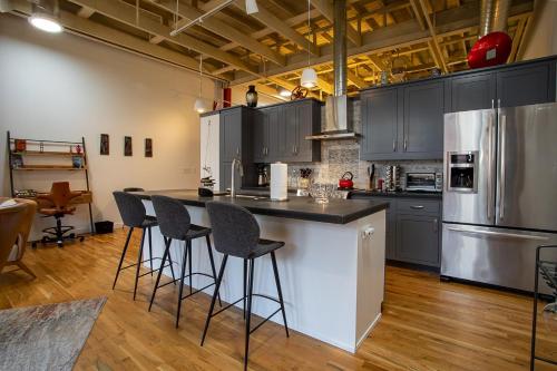 a kitchen with gray cabinets and a island with bar stools at The Press Loft in Asheville