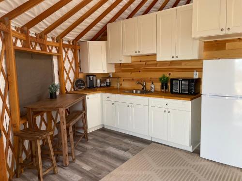 a kitchen with white cabinets and a table and a refrigerator at Yurt Escape with Amazing Country Views in Temecula