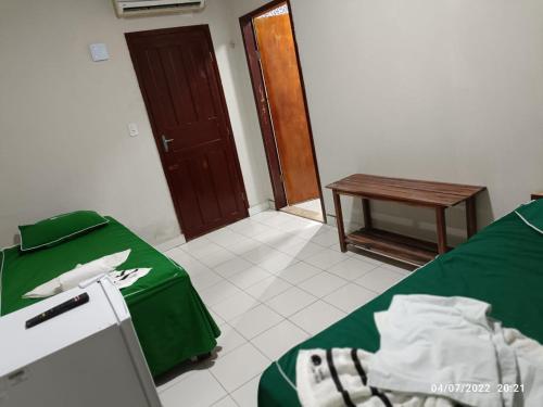 a room with two beds and a table and a door at Pousada Recanto Beach in Camocim
