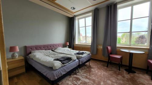 1 dormitorio con cama, mesa y ventanas en Mellanbrons B&B en Åmål