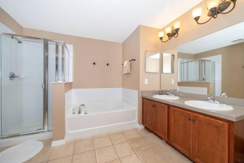 een badkamer met een bad, 2 wastafels en een douche bij Pool, Disney, Fast Wi-Fi - World Class 3-bed Home in Kissimmee