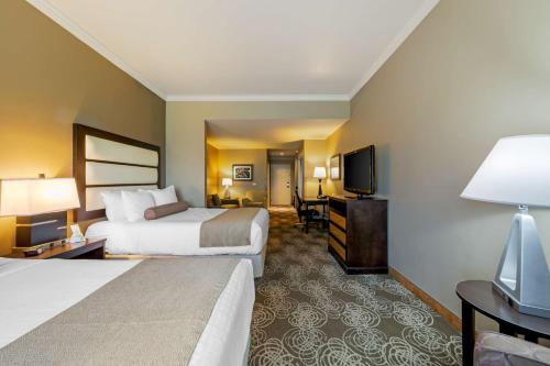 a hotel room with two beds and a flat screen tv at Best Western Plus Miami Airport North Hotel & Suites in Miami