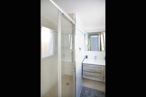 y baño con ducha acristalada y lavamanos. en Superbe appartement à 2 pas des Halles, Climatisé, terrasse, garage, en Narbona