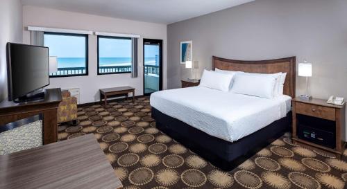 a hotel room with a bed and a flat screen tv at Best Western New Smyrna Beach Hotel & Suites in New Smyrna Beach