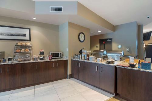 a kitchen with wooden cabinets and a clock on the wall at Best Western Plus Revelstoke in Revelstoke