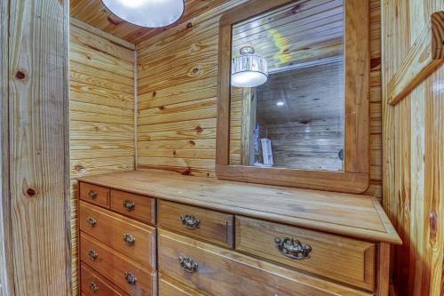 a log cabin bathroom with a mirror and a dresser at The Gemini-a dreamy, waterfront tiny cabin in Rogersville