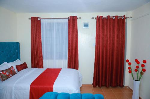 a bedroom with red drapes and a bed with white and red sheets at Executive studio in Ruiru in Ruiru