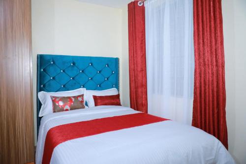 sypialnia z łóżkiem z czerwonym i niebieskim zagłówkiem w obiekcie Executive studio in Ruiru w mieście Ruiru