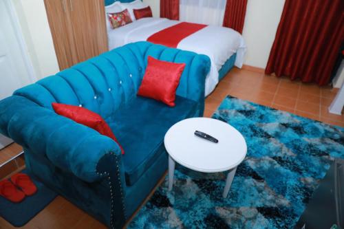 a living room with a blue couch and a bed at Executive studio in Ruiru in Ruiru