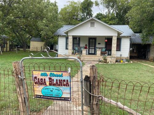 a house with a sign in front of a fence at 11th St. Casa Blanca Bandera, TX. in Bandera