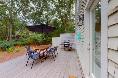 a patio with a table and chairs and an umbrella at Seabury Serenity in New Seabury