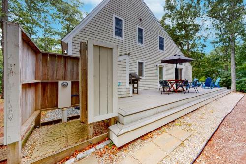 a house with a wooden deck with a table and chairs at Seabury Serenity in New Seabury