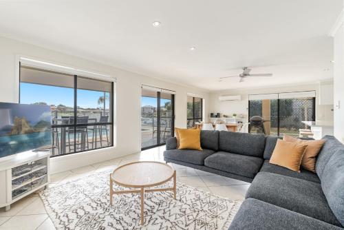 a living room with a couch and a table at Sandy Shores - Absolute Waterfront & Swimming pool - Holiday Yamba in Yamba