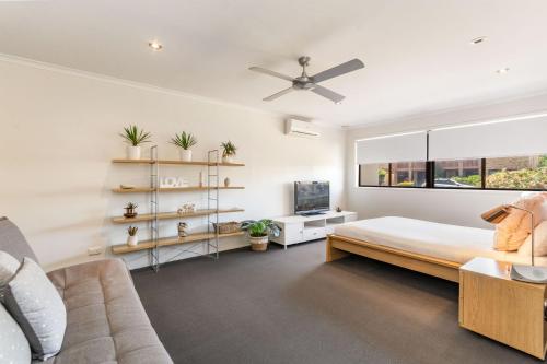 a bedroom with a bed and a couch and a window at Sandy Shores - Absolute Waterfront & Swimming pool - Holiday Yamba in Yamba