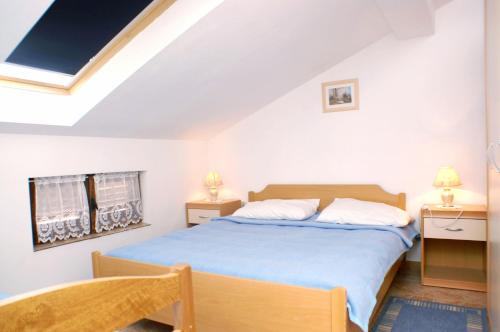 een slaapkamer met een bed, 2 tafels en een raam bij Family friendly seaside apartments Vlasici, Pag - 4319 in Vlašići
