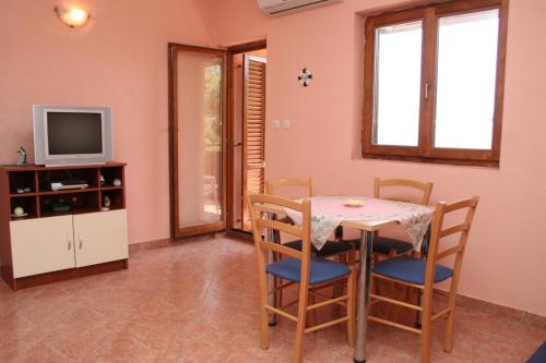 a dining room with a table and chairs and a tv at Apartments by the sea Sveta Nedilja, Hvar - 4609 in Sveta Nedelja